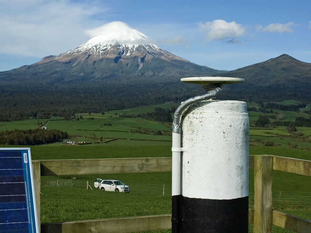 A GNSS antenna mounted on a pillar with Mt Taranaki in the background.